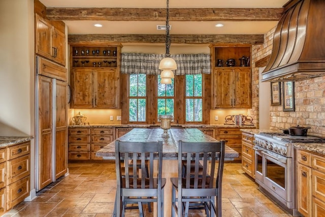 kitchen with premium range hood, high end appliances, brown cabinets, and stone tile flooring