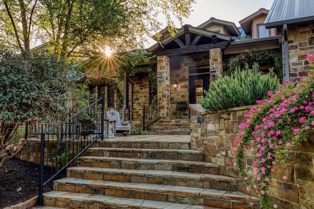 entrance to property featuring stone siding and metal roof