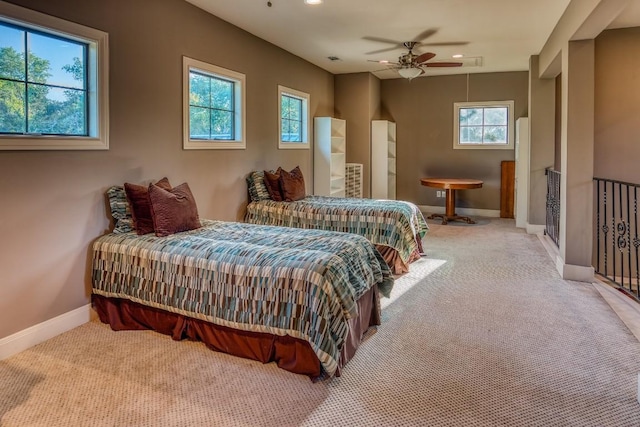 carpeted bedroom with attic access, a ceiling fan, baseboards, and multiple windows