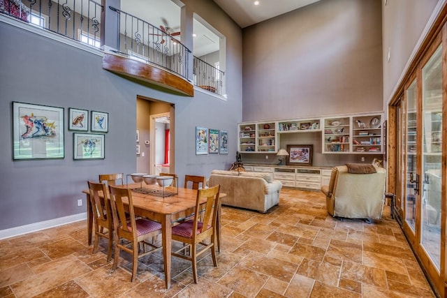 dining space featuring baseboards, stone tile floors, and a towering ceiling