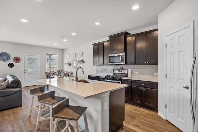 337 Akumal St, Leander, TX 78641 - kitchen with stainless steel appliances, a sink, a kitchen bar, open floor plan, and light wood-style flooring