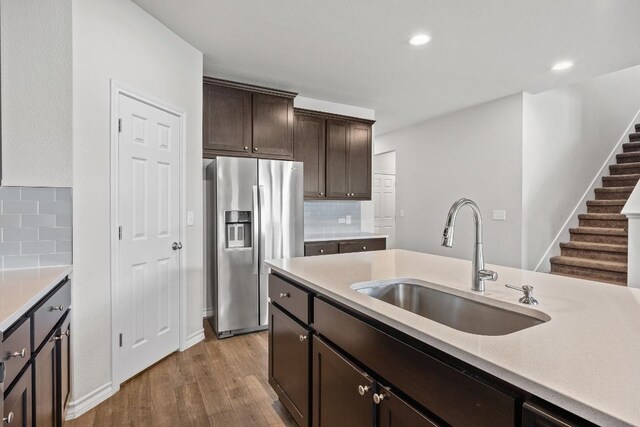 337 Akumal St, Leander, TX 78641 - kitchen featuring stainless steel fridge, a sink, light wood-style floors, decorative backsplash, and dark brown cabinetry