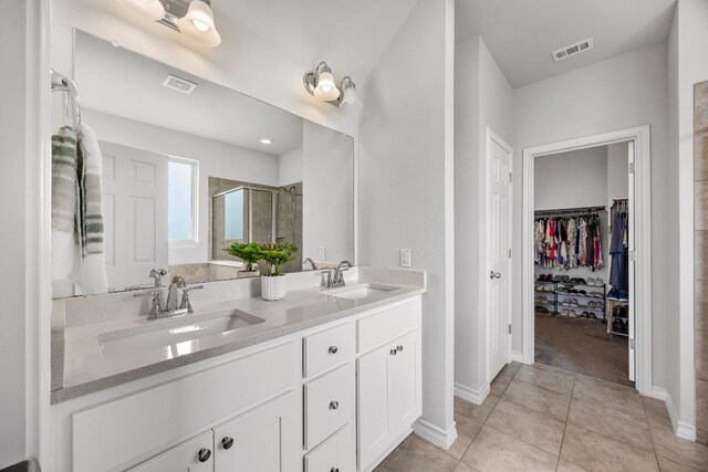 337 Akumal St, Leander, TX 78641 - bathroom with a stall shower, a walk in closet, double vanity, baseboards, and tile patterned floors