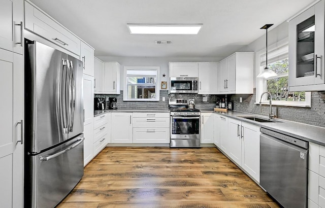 kitchen with a sink, stainless steel appliances, backsplash, white cabinetry, and visible vents
