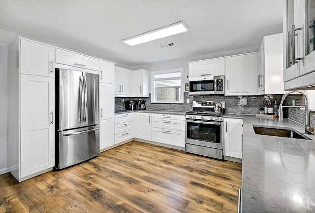 1318 Contour Dr, Burnet, TX 78611 - kitchen with stainless steel appliances, tasteful backsplash, white cabinets, and wood finished floors
