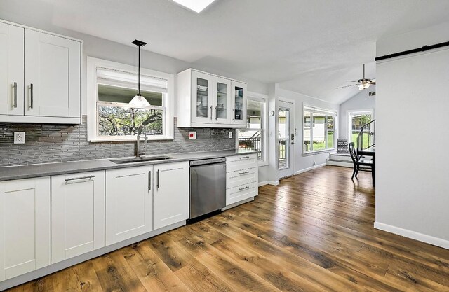 kitchen with dishwasher, a sink, baseboards, tasteful backsplash, and white cabinetry