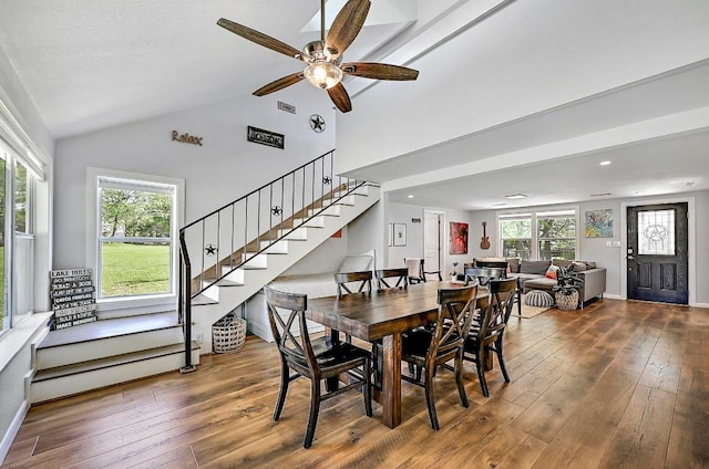 dining area featuring vaulted ceiling, visible vents, wood-type flooring, stairs, and ceiling fan
