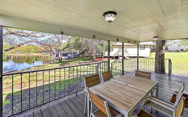 wooden terrace with a lawn, outdoor dining area, and a water view