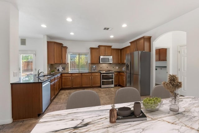116 Silkstone St, Hutto, TX 78634 - kitchen with appliances with stainless steel finishes, plenty of natural light, backsplash, brown cabinetry, and recessed lighting