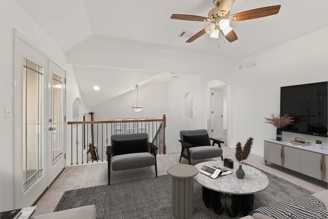 living area featuring light colored carpet, arched walkways, a ceiling fan, and lofted ceiling