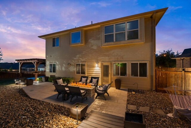back of property at dusk featuring fence, a fire pit, a pergola, and a patio area
