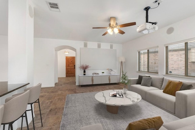 living area with arched walkways, visible vents, and ceiling fan