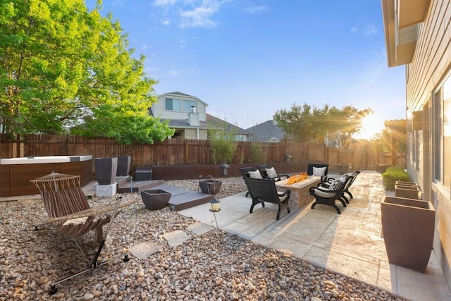 view of patio / terrace with a fire pit, a fenced backyard, and a jacuzzi