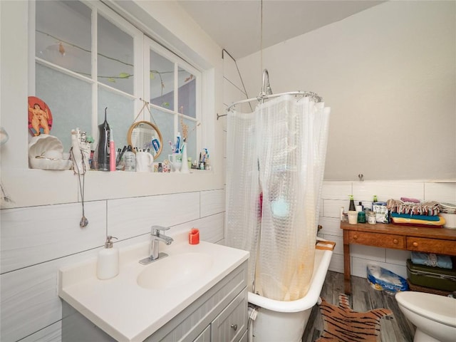 bathroom featuring shower / bath combo, vanity, tile walls, a wainscoted wall, and toilet