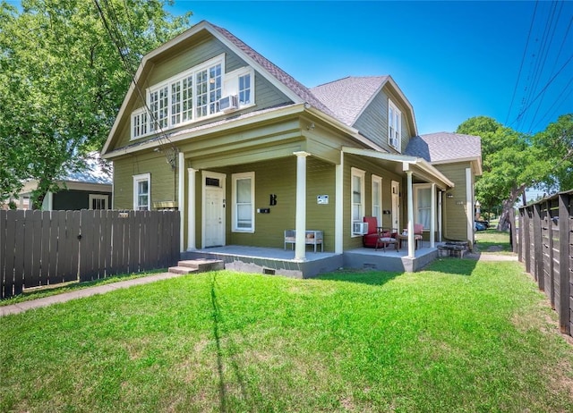 view of front of property featuring a front lawn, roof with shingles, fence, and covered porch