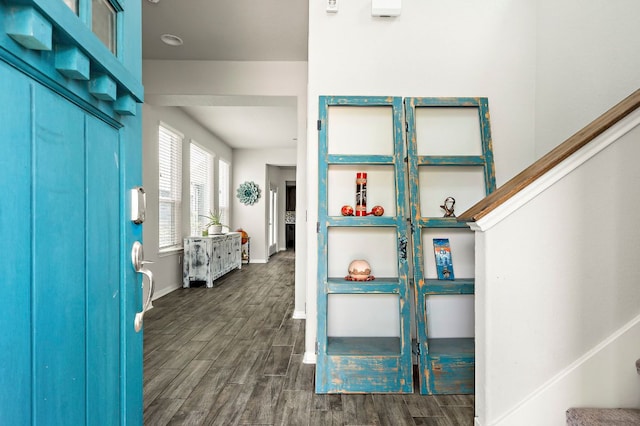 entryway with dark wood finished floors, baseboards, and stairs