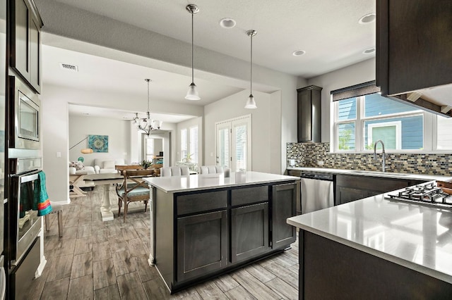 kitchen with decorative backsplash, a sink, visible vents, stainless steel appliances, and light countertops