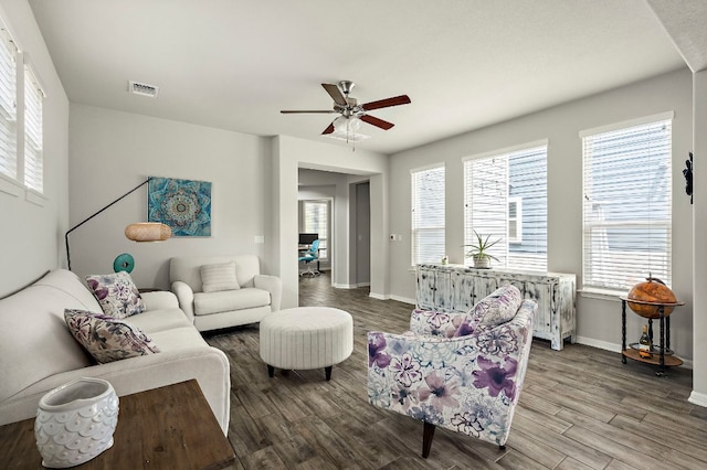 living area featuring baseboards, visible vents, wood finished floors, and ceiling fan