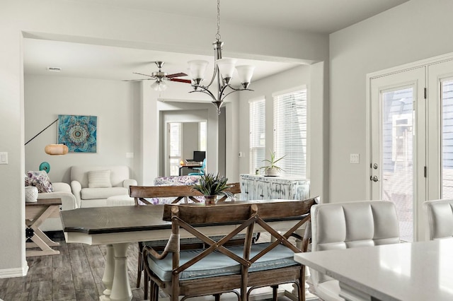 dining area featuring visible vents, wood finished floors, and ceiling fan with notable chandelier