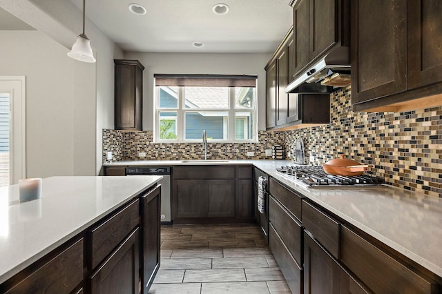 kitchen with dark brown cabinetry, stainless steel appliances, under cabinet range hood, light countertops, and a sink