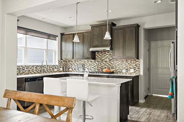 kitchen featuring tasteful backsplash, stainless steel appliances, light countertops, dark brown cabinets, and a sink