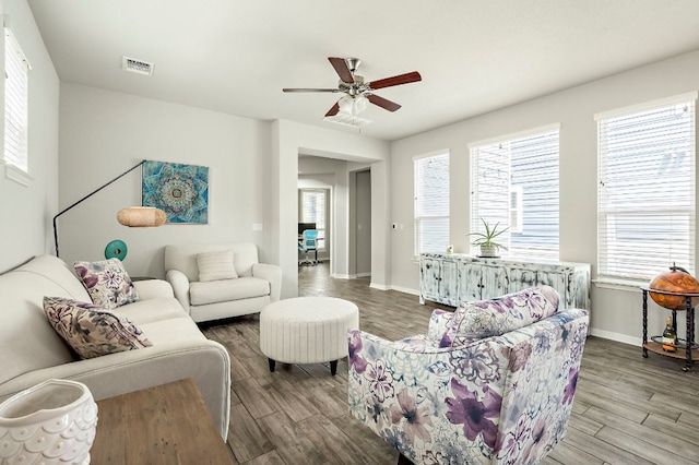 living area with wood finished floors, visible vents, ceiling fan, and baseboards