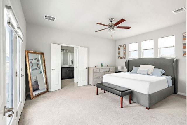 bedroom with connected bathroom, visible vents, ceiling fan, and light carpet