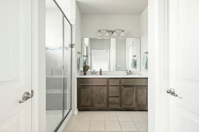 full bathroom featuring double vanity, a stall shower, tile patterned flooring, and a sink