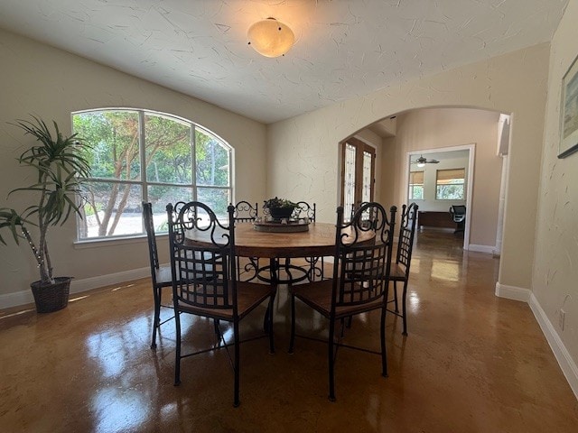 dining room with arched walkways, healthy amount of natural light, finished concrete floors, and baseboards