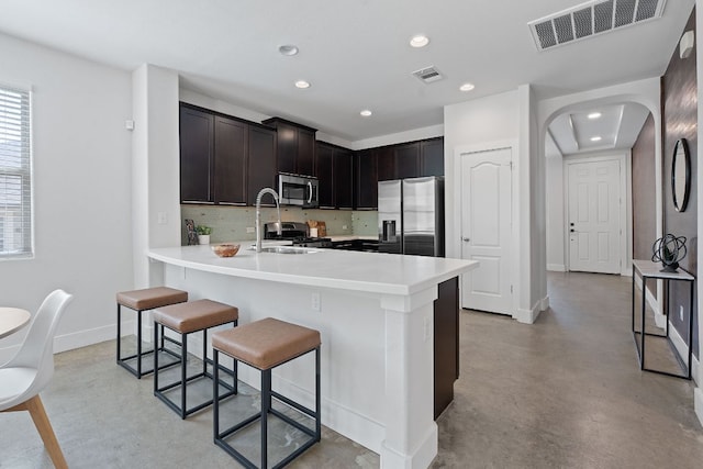 6224 Aviara Dr Unit E14, Austin, TX 78735 - kitchen featuring appliances with stainless steel finishes, finished concrete flooring, a kitchen bar, recessed lighting, and arched walkways