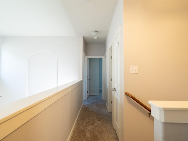corridor with carpet flooring, baseboards, and an upstairs landing