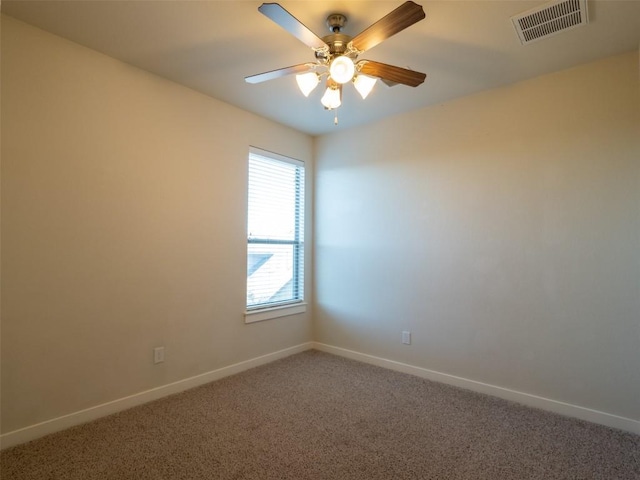 empty room with carpet floors, a ceiling fan, visible vents, and baseboards