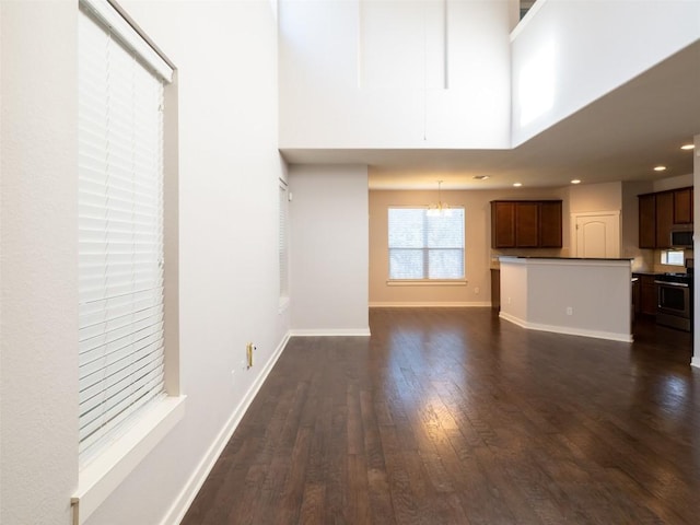 unfurnished living room with baseboards, dark wood-style floors, recessed lighting, and a notable chandelier