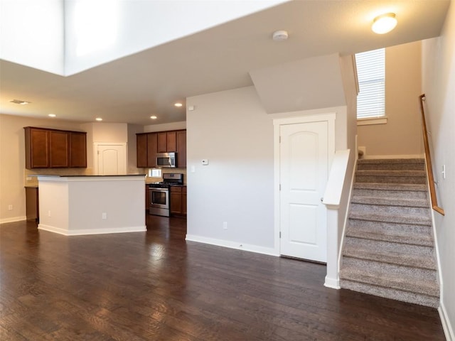 unfurnished living room featuring recessed lighting, dark wood finished floors, stairway, and baseboards