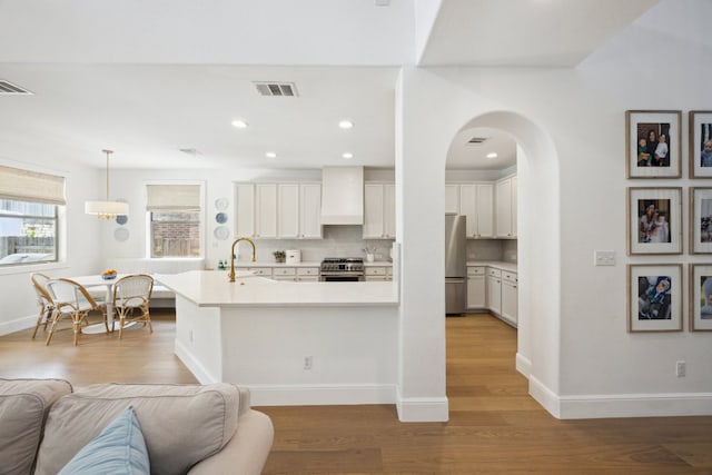 kitchen featuring appliances with stainless steel finishes, light wood-style flooring, custom range hood, light countertops, and recessed lighting