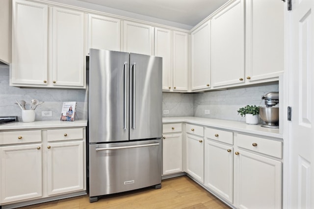 kitchen featuring freestanding refrigerator, light countertops, tasteful backsplash, white cabinets, and light wood-style floors