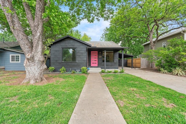 bungalow with fence, a porch, a front yard, and concrete driveway