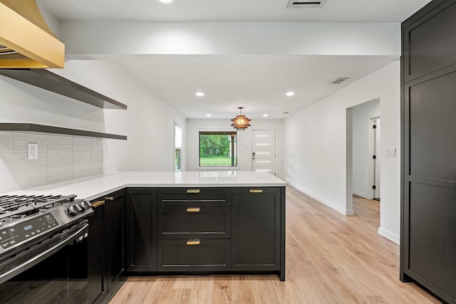 kitchen with open shelves, a peninsula, light countertops, and gas range
