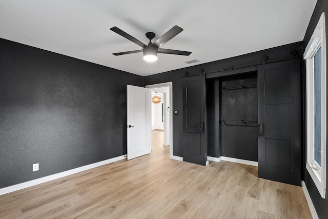 unfurnished bedroom with a closet, light wood-type flooring, ceiling fan, baseboards, and visible vents