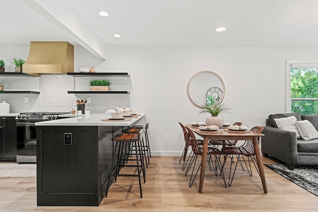 5602 Joe Sayers Ave, Austin, TX 78756 - kitchen with stainless steel gas stove, open shelves, custom exhaust hood, dark cabinets, and a kitchen bar