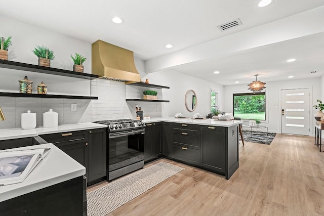 5602 Joe Sayers Ave, Austin, TX 78756 - kitchen featuring stainless steel gas range, open shelves, light countertops, light wood-style flooring, and wall chimney exhaust hood