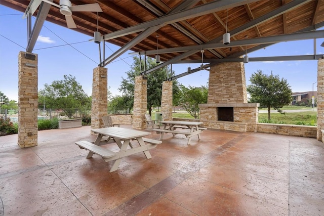 view of patio featuring an outdoor stone fireplace and a ceiling fan