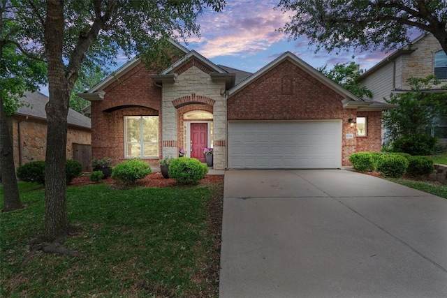 view of front of property featuring concrete driveway, an attached garage, stone siding, brick siding, and a front yard