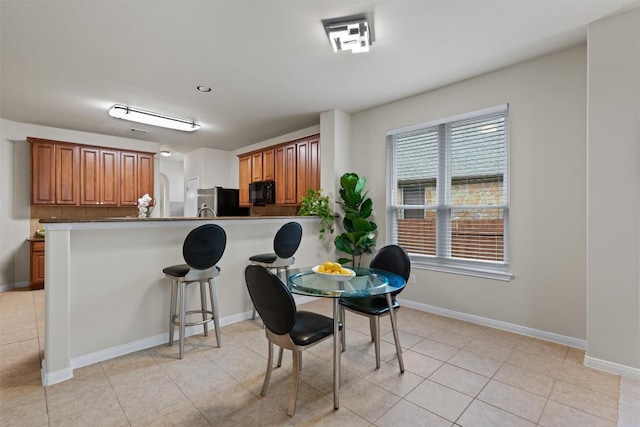 dining space with baseboards and light tile patterned floors