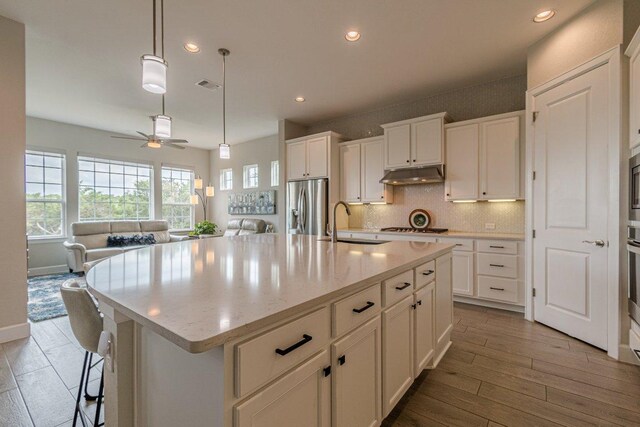 513 Freeing Oak St, San Marcos, TX 78666 - kitchen with appliances with stainless steel finishes, under cabinet range hood, a sink, a ceiling fan, and backsplash