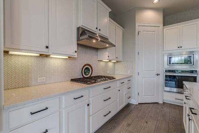 513 Freeing Oak St, San Marcos, TX 78666 - kitchen featuring stainless steel appliances, under cabinet range hood, dark wood finished floors, white cabinetry, and light stone counters