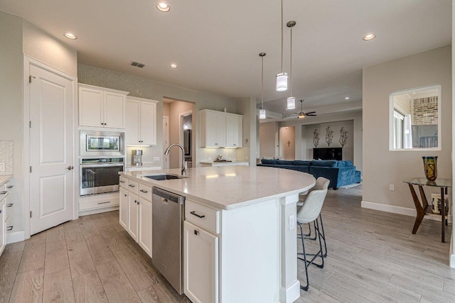 513 Freeing Oak St, San Marcos, TX 78666 - kitchen with appliances with stainless steel finishes, a sink, light wood-style flooring, an island with sink, and recessed lighting