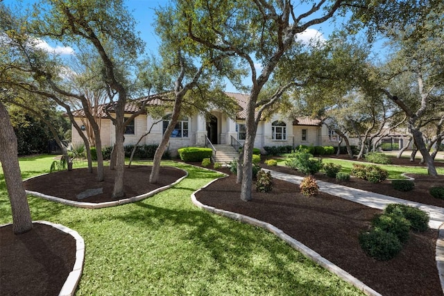 view of front facade with a tile roof, a front lawn, and stucco siding