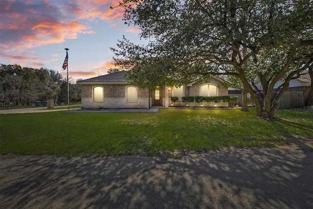 view of front of home featuring fence, a lawn, and stone siding