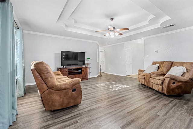 living room with a ceiling fan, wood finished floors, a tray ceiling, baseboards, and visible vents